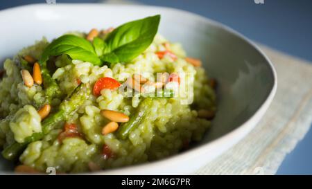 Risotto mit grünem Pesto. Risotto ist ein norditalienisches Reisgericht, das mit Brühe zubereitet wird, bis es eine cremige Konsistenz erreicht. Stockfoto