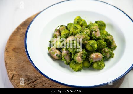 Gnocchi mit Pesto-Sauce und gegrillten Schweinewürsten. Stockfoto