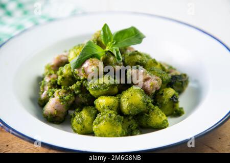 Gnocchi mit Pesto-Sauce und gegrillten Schweinewürsten. Stockfoto