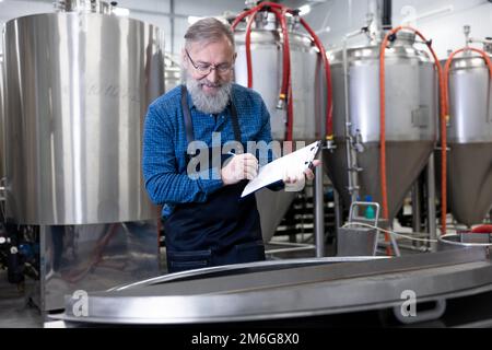 Reifer Fabrikarbeiter, der den Brauereiprozess kontrolliert und involviert wirkt Stockfoto