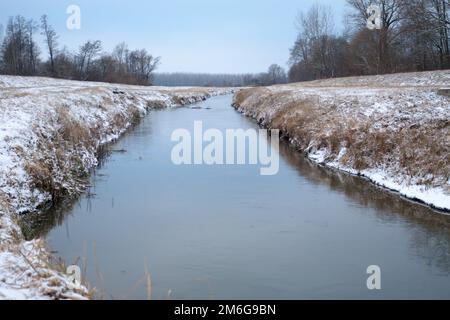 Winter Schneefall Flusslandschaft. Morgen über dem verschneiten Winterfluss. Fluss im Winter. Stockfoto