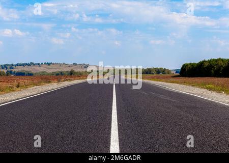 Gerade asphaltierte Straße mit Markierungen, die in die Ferne durch Stockfoto