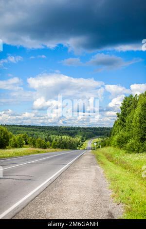 Gerade asphaltierte Straße mit Markierungen, die in die Ferne durch Stockfoto