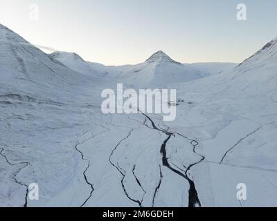 Schneebedeckte Landschaft in der Nähe von Dalvik in Island / 2022. Dezember / gefrorener Bach Stockfoto