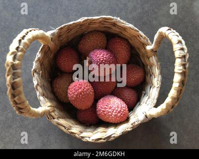 Kleiner Strohkorb mit roten Litschis Stockfoto