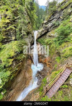 Hölzerner Fußweg als Brücke über rauschenden Wasserfall Stockfoto