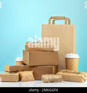 Umweltfreundlicher Einkaufs- und Lieferservice. Handgefertigte Geschenkboxen aus Pappe, Papierbeutel und Pappbecher mit Kaffee auf blauem Hintergrund. Null War Stockfoto