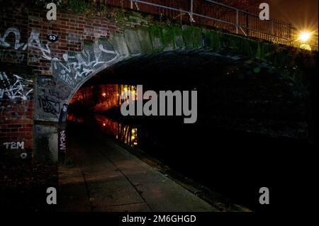 Blick auf einen Fußweg unter einer Brücke am Regent's Canal bei Nacht in North London, Camden Stockfoto