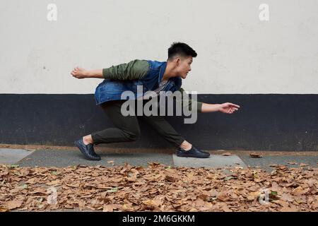 Ein junger asiatischer Tänzer zieht in eine Londoner Straße Stockfoto