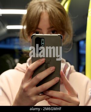 Parchim, Deutschland. 04. Januar 2023. Auf einer Presseveranstaltung der Verkehrsbetriebe Ludwigslust-Parchim zur Präsentation des kostenlosen WLAN in Bussen hält Marie Wolf, eine Mitarbeiterin, ein Mobiltelefon in einem Bus. Alle elektrischen Busse, die von der öffentlichen Verkehrsgesellschaft betrieben werden, müssen mit dem kostenlosen WLAN ausgestattet sein. Kredit: Bernd Wüstneck/dpa/Alamy Live News Stockfoto