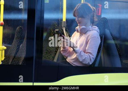 Parchim, Deutschland. 04. Januar 2023. Auf einer Presseveranstaltung der öffentlichen Verkehrsgesellschaft Ludwigslust-Parchim, um das kostenlose WLAN in Bussen zu präsentieren, sitzt Marie Wolf, eine Mitarbeiterin, mit einem Handy in einem Bus. Alle Elektrobusse, die von der öffentlichen Verkehrsgesellschaft betrieben werden, müssen mit einem WLAN ausgestattet sein. Kredit: Bernd Wüstneck/dpa/Alamy Live News Stockfoto