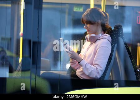 Parchim, Deutschland. 04. Januar 2023. Auf einer Presseveranstaltung der öffentlichen Verkehrsgesellschaft Ludwigslust-Parchim, um das kostenlose WLAN in Bussen zu präsentieren, sitzt Marie Wolf, eine Mitarbeiterin, mit einem Handy in einem Bus. Alle elektrischen Busse, die von der öffentlichen Verkehrsgesellschaft betrieben werden, müssen mit dem kostenlosen WLAN ausgestattet sein. Kredit: Bernd Wüstneck/dpa/Alamy Live News Stockfoto