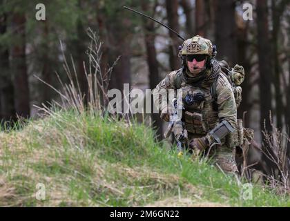 Bemowo Piskie Training Area, Orzysz, Polen - Sgt. Nile Adams, Soldat Teil der Bravo Company, 185. Infanterie Regiment, California Army National Guard, springt während des letzten Trainingstages von Training Thunderbolt Focus 2022, April 27, auf eine neue taktische Position. USA Soldaten unter anderem aus alliierten Nationen arbeiteten in dynamischen Teams gegen Taktiken, Techniken und Verfahren der feindlichen Kräfte zusammen, die es den Gefechtsverbänden ermöglichten, alle Kampffähigkeiten, Interoperabilität und Kontrollfähigkeiten zu üben, zu verfeinern und zu validieren. Stockfoto