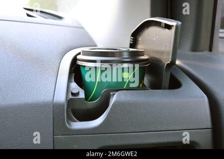 Ein Glas Kaffee mit Ihnen auf der Straße im Getränkehalter des Autos Stockfoto