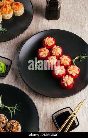 Verschiedene Arten von Sushi-Rollen in Tellern auf dem Tisch. sojasoße, Stockfoto