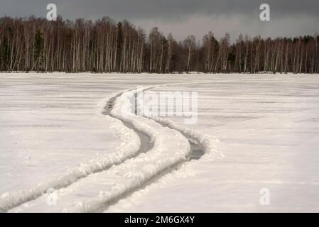 Gewundene Radspuren auf einem gefrorenen See. Wintertag. Stockfoto