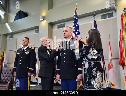 Chief Warrant Officer 5 Mark A. Joiner, Georgia Army National Guard, steht während seiner Beförderungszeremonie am 28. April 2022 im Clay National Guard Center in Marietta, Georgia, auf dem Laufenden, während der Erzähler den offiziellen Befehl liest und seine Familie seinen neuen Rang anheftet Die Beförderungszeremonie des Chief Warrant Officer 5 Joiner fand vor seiner Übernahme der Verantwortung als Chief Warrant Officer der Staatsanwaltschaft statt ARNG. Stockfoto