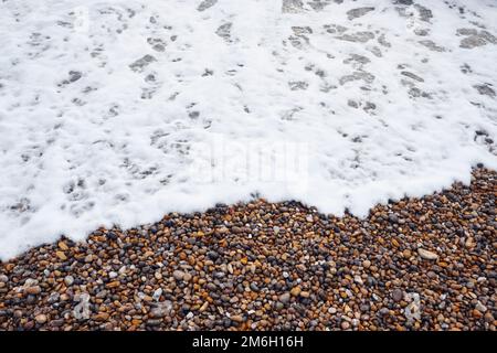 Aus nächster Nähe, wenn die schäumende Brandung über einen Strand für Menschen an der englischen Südküste angespült wird Stockfoto