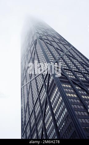 Details des John Hancock Gebäudes von unten zu sehen, während es im Winter an einem grauen Tag in einer nebeligen Wolke verschwindet Stockfoto