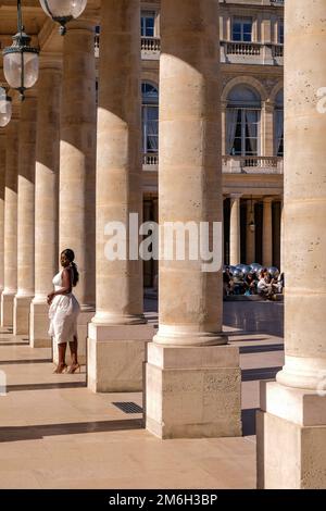 Junge Schwarze, die für Fotos in einem weißen Kleid posiert, in den Säulen des Palais Royal in Paris, Frankreich - Mode, Influencer Stockfoto