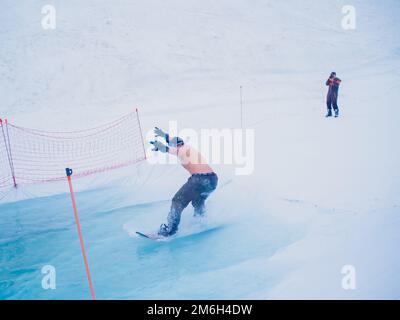 Russland, Sotschi 11.05.2019. Ein Mann ohne Oberbekleidung fährt auf dem Wasser mit einem Snowboard. Du musst nicht hinfallen und bis zum Ende fahren Kra Stockfoto