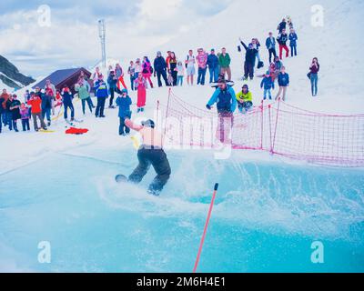 Russland, Sotschi 11.05.2019. Ein Mann ohne Oberbekleidung fährt auf dem Wasser mit einem Snowboard. Das Publikum beobachtet und fotografiert ihn Stockfoto