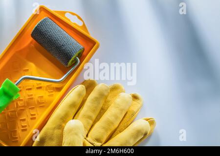 Lederschutzhandschuhe Farbwanne Rolle auf weißer Oberfläche. Stockfoto