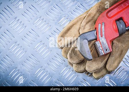 Schutzhandschuhe aus Leder Rohrzange auf kanalisiertem Metallhintergrund Baukonzept. Stockfoto