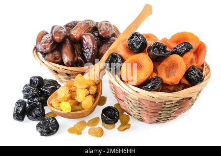 Getrocknete Aprikosen in einem Korb und andere getrocknete Früchte auf einem weißen Teller mit weichem Schatten Stockfoto