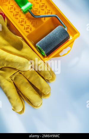 Satz Lederschutzhandschuhe, Rolle für Farbwanne auf weißem Hintergrund. Stockfoto