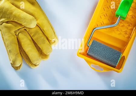 Set aus Lederschutzhandschuhen, Rolle für Farbablage auf weißem Hintergrund. Stockfoto