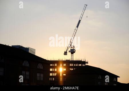 Die Sonne geht hinter einem silhouetten Gebäude unter, das in London gebaut wird Stockfoto