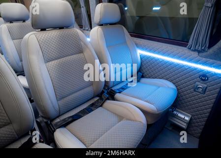 Komfortables Interieur für Personenbusse mit gepolsterten Sitzen; individueller Transfer für eine Gruppe von Personen; Umbau des Innenraums eines Lkws; Stockfoto