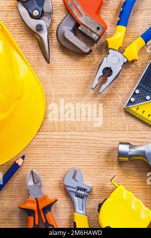 Vertikalansicht Handschuh Abschneider Affenschlüssel Zange Lineal Hammer Tapelinschneider Helmbleistift mit kleinem Kopierraum auf Holzbretter Baukonzept Stockfoto