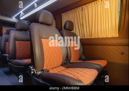 Komfortables Interieur für Personenbusse mit gepolsterten Sitzen; individueller Transfer für eine Gruppe von Personen; Umbau des Innenraums eines Lkws; Stockfoto