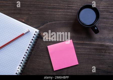 Weißer Notizblock, Bleistifterinnerung und Tasse schwarzen Kaffee auf Pinienholz, Bürokonzept Stockfoto