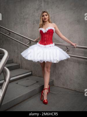 Ballerina trägt High Heels und weihnachtskleid posiert im Freien Stockfoto