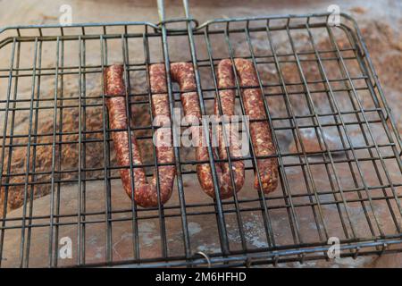 Leckeres gegrilltes Fleisch über den Kohlen auf einem Barbecue. Leckere Würstchen. Mowani Camping, Damaraland, Namibia. Stockfoto