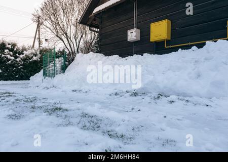 Gas- und Strombox auf einem Holzhaus inmitten des Schnees Stockfoto