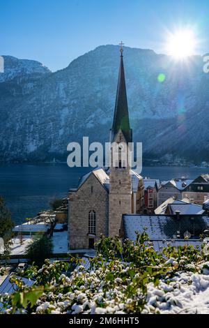 Schöne sonnige Stadtlandschaft der besonderen Stadt Hallstatt in Österreich Salzkammergut verschneite Winterberge und See und Kirche. Stockfoto