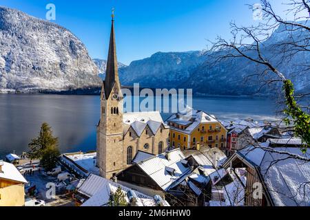 Schöne sonnige Stadtlandschaft der besonderen Stadt Hallstatt in Österreich Salzkammergut verschneite Winterberge und See und Kirche. Stockfoto