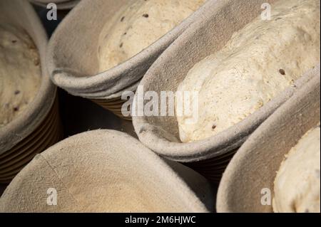 Nahaufnahme von rohem Vollkornbrotteig in einer mit Backtuch ausgelegten Schale. Handwerkliche Bäckerei. Gesunde und gesunde Lebensmittel Stockfoto