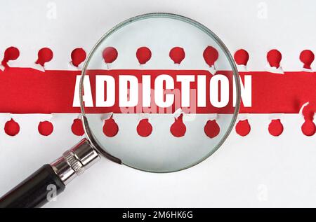 Zwischen zwei Blättern aus einem Notizbuch auf einem roten Streifen mit der Inschrift "sucht" befindet sich eine Lupe. Stockfoto