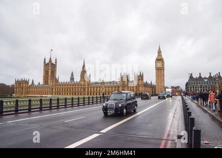 London, Großbritannien. 3. Januar 2023 Ein schwarzes Taxi fährt an den Houses of Parliament und Big Ben auf der Westminster Bridge vorbei. Stockfoto