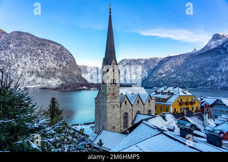 Wunderschönes Stadtbild der besonderen Stadt Hallstatt in Österreich Salzkammergut verschneite Winterberge und See und Kirche. Stockfoto