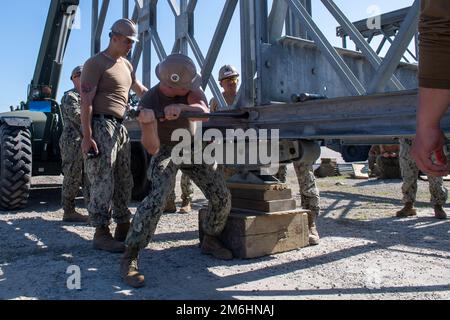 GULFPORT, Fräulein. (28. April 2022) Ingenieurassistent Brian Hemme der Klasse 1. aus Murrieta, Kalifornien, dem Naval Mobile Construction Battalion (NMCB) 1 zugeteilt, schlägt während der Montage eines Mabey Johnson Bridge Trainingskurses an Bord des Naval Construction Training Center Gulfport einen Haltestift in Position. Die NMCB 1 führt einen intensiven Schulungsplan für Homeporte durch, um ihre Fähigkeit zur Durchführung von Bau-, humanitären und Theatereinsätzen zu erweitern. Stockfoto