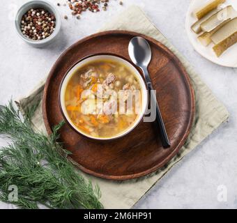 Traditionelle russische Suppe mit eingelegten Gurken. Gurke mit Perlgerste und Fleisch auf hellem Hintergrund mit frischem Dill und Gewürzen. Draufsicht Stockfoto