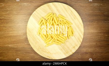 Penne Rigate Raw Pasta ist eine kurze Pasta mit schrägen Schnitten und einer gerippten Oberfläche. Traditionelle italienische Pasta. Nudelhintergrund. Oben Stockfoto