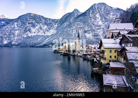 Schöne sonnige Stadtlandschaft der besonderen Stadt Hallstatt in Österreich Salzkammergut verschneite Winterberge und See und Kirche. Stockfoto