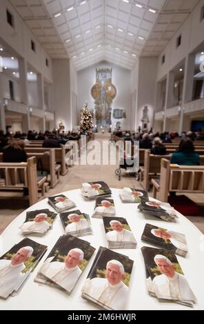 Stuttgart, Deutschland. 04. Januar 2023. Zahlreiche Bilder von Papst Emeritus Benedict XVI., der gestorben ist, liegen auf einem Tisch im Eingangsbereich der Kathedrale St. Eberhard. Besucher feierten ein päpstliches Requiem für Papst Benedikt XVI. In der Kathedrale. Kredit: Christoph Schmidt/dpa/Alamy Live News Stockfoto